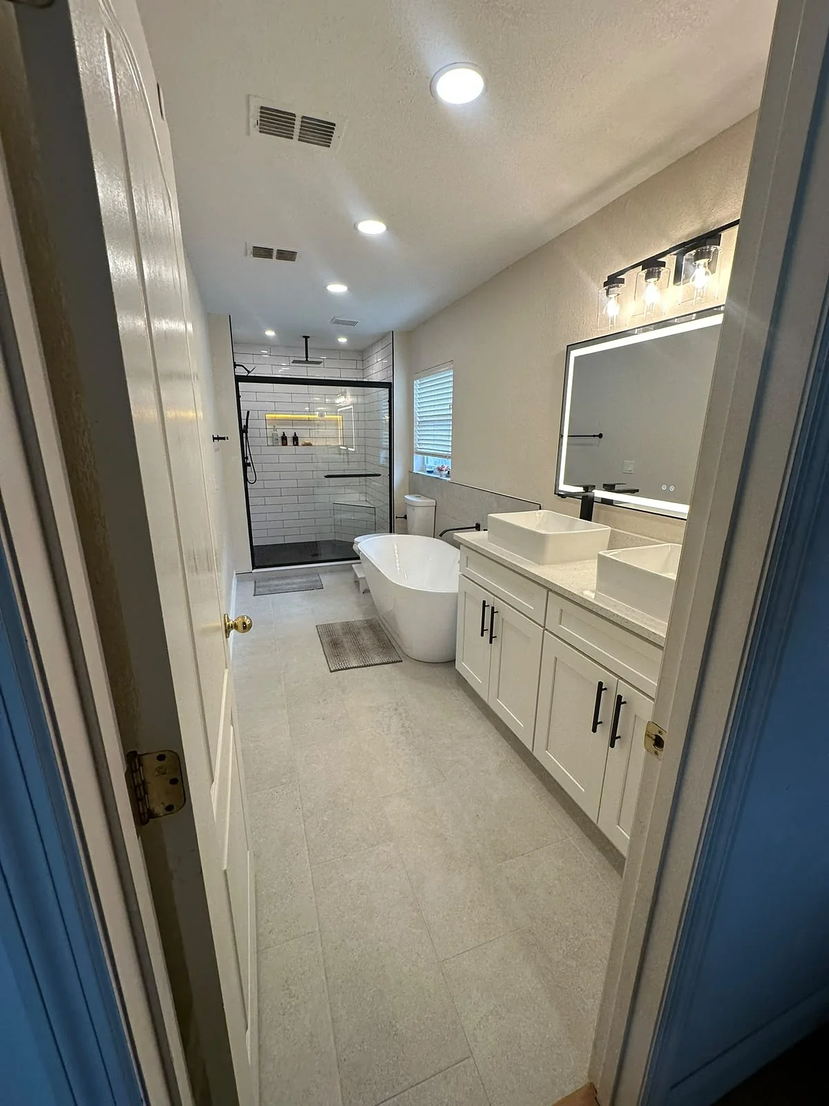 Remodeled bathroom with freestanding tub, double sink vanity and LED mirror