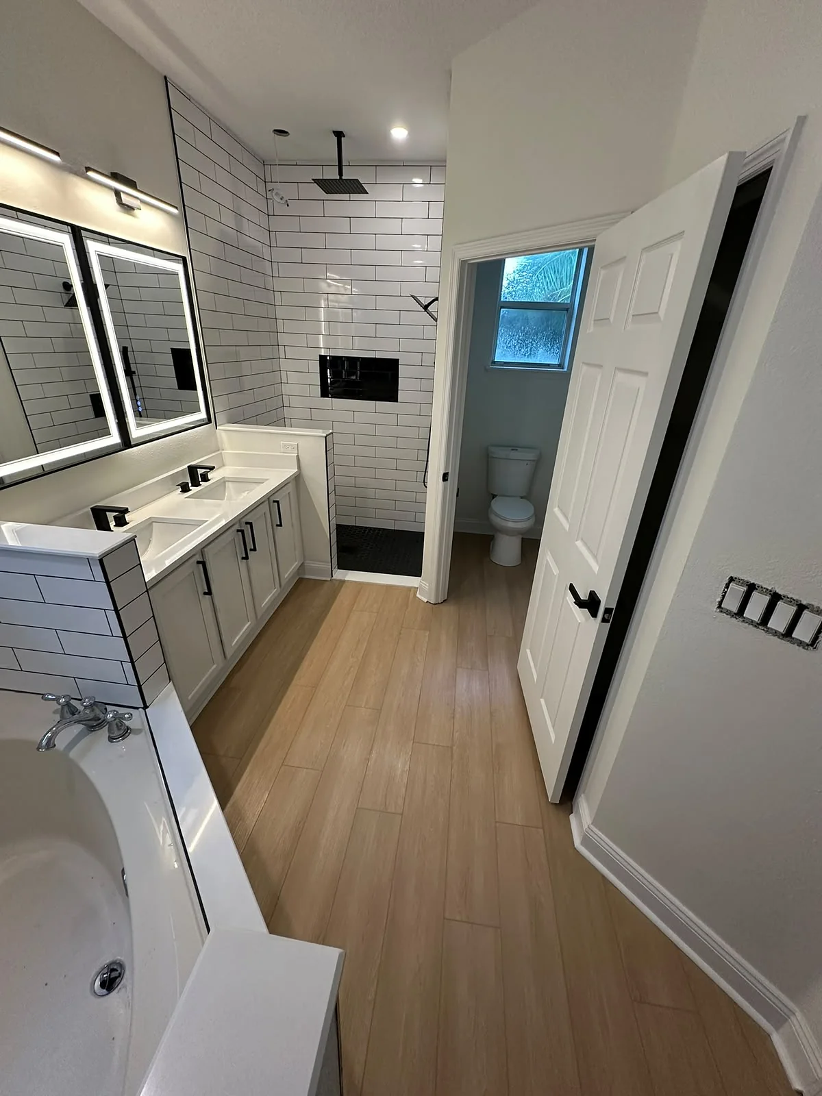 Remodeled bathroom with white subway tile, double vanity and lighted mirrors
