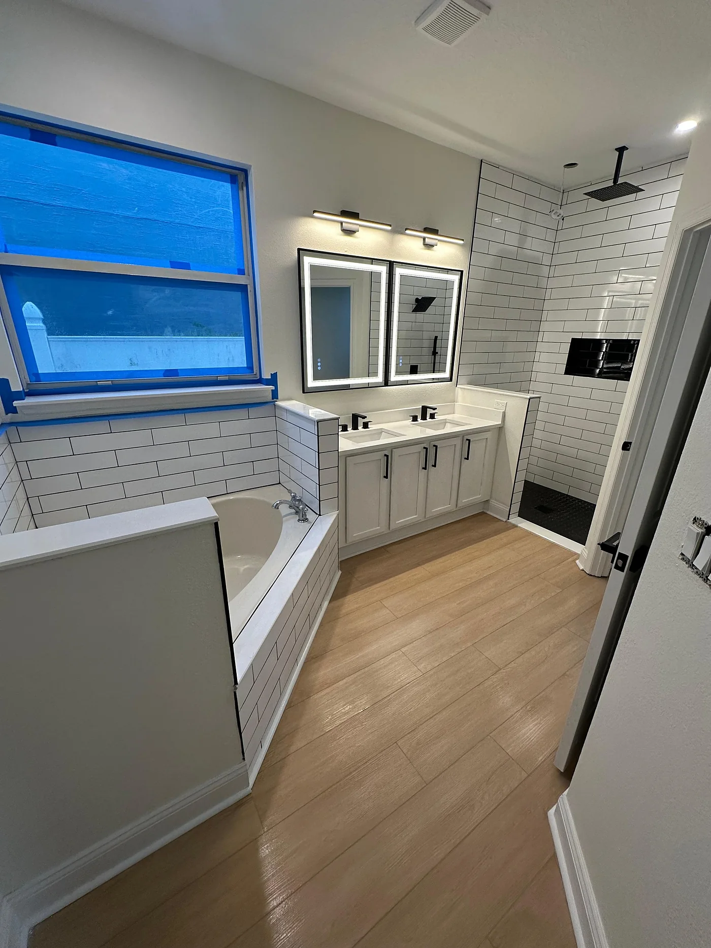 Remodeled bathroom with subway tile shower, soaking tub and double vanity
