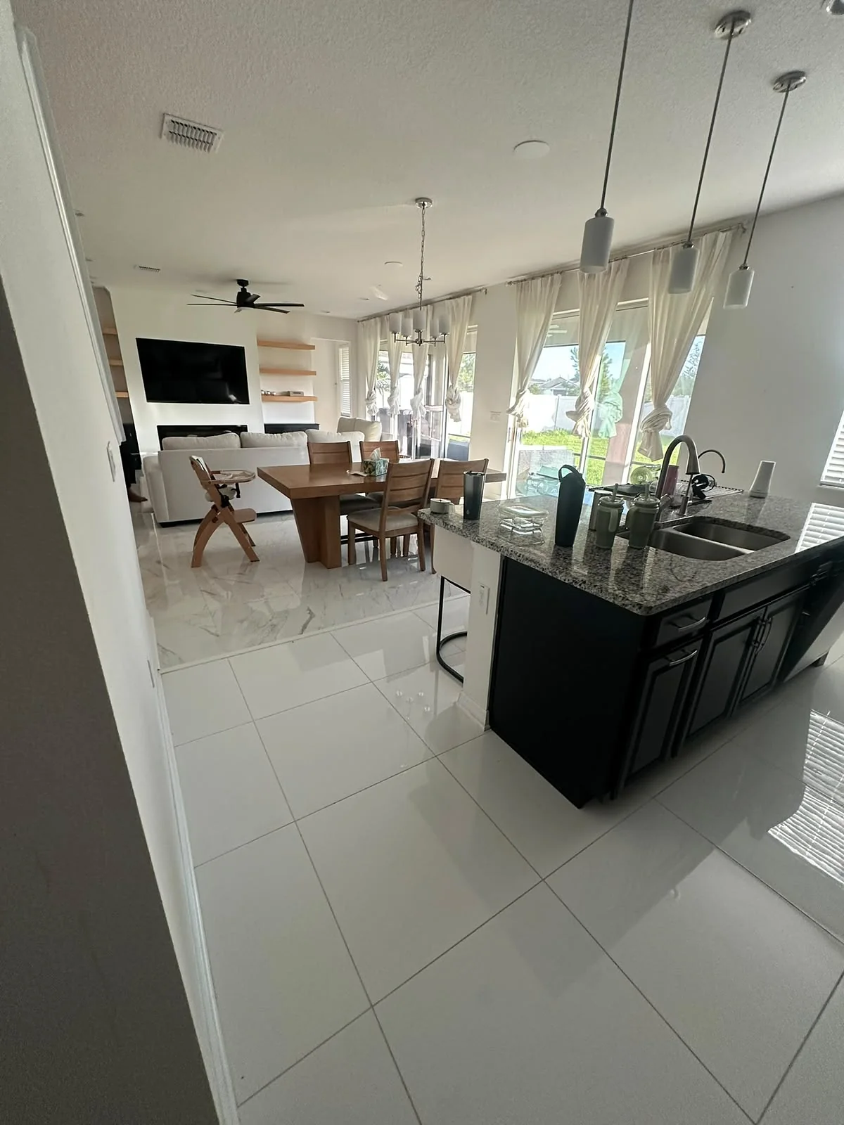 Open kitchen with dark island cabinets and large porcelain tile floor