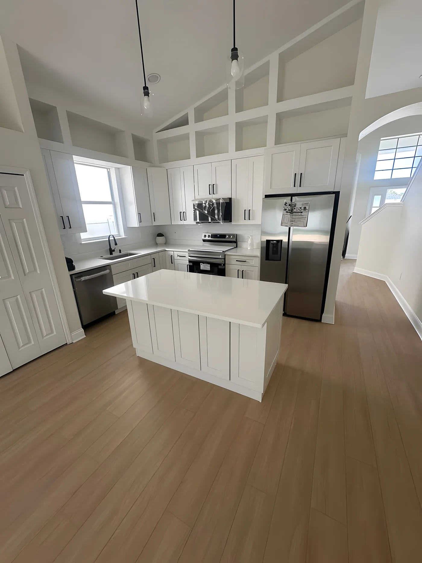 White kitchen with island and new light wood-look flooring
